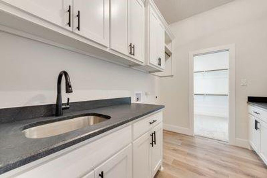 Kitchen with white cabinetry, sink, and light wood-type flooring