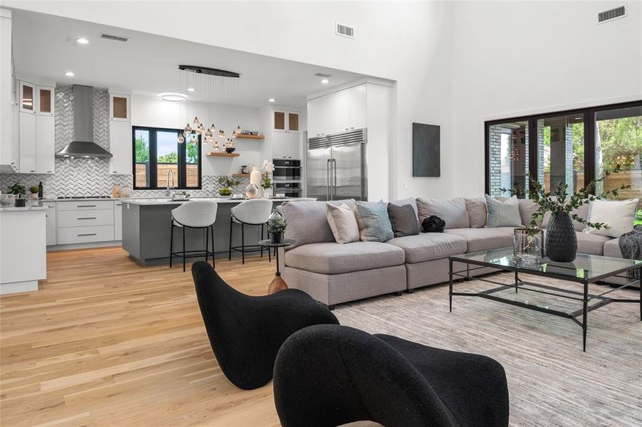 Living room featuring a healthy amount of sunlight, light hardwood / wood-style floors, a towering ceiling, and sink