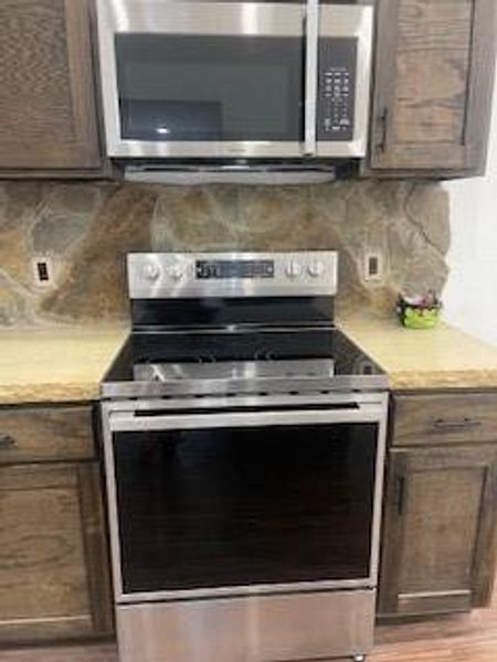 Kitchen featuring dark brown cabinets, light hardwood / wood-style flooring, tasteful backsplash, and electric range