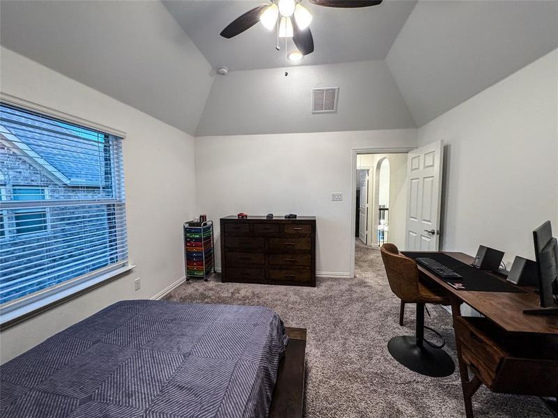 Bedroom with carpet floors, ceiling fan, and vaulted ceiling