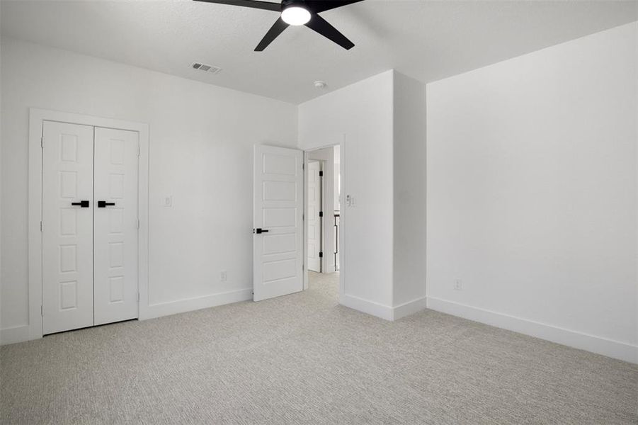 Unfurnished bedroom featuring a closet, ceiling fan, and light colored carpet