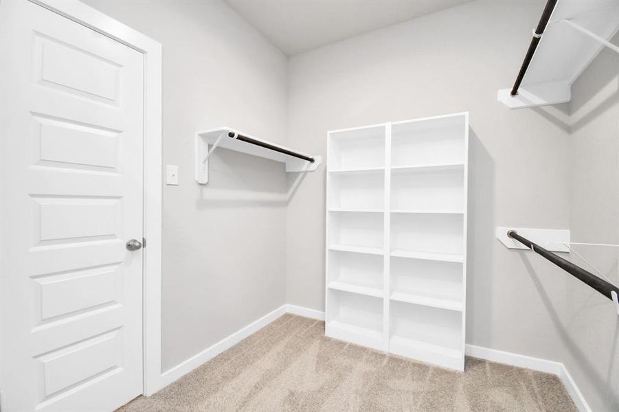 Discover luxury in this expansive walk-in closet, adorned with high ceilings and luxurious carpet. Sample photo of completed home with similar floor plan. Actual colors and selections may vary.