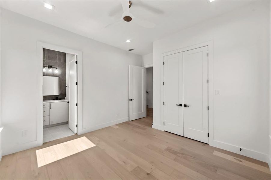 Secondary Bedroom on 1st floor with ceiling fan, light wood-type flooring, ensuite bath, and a closet