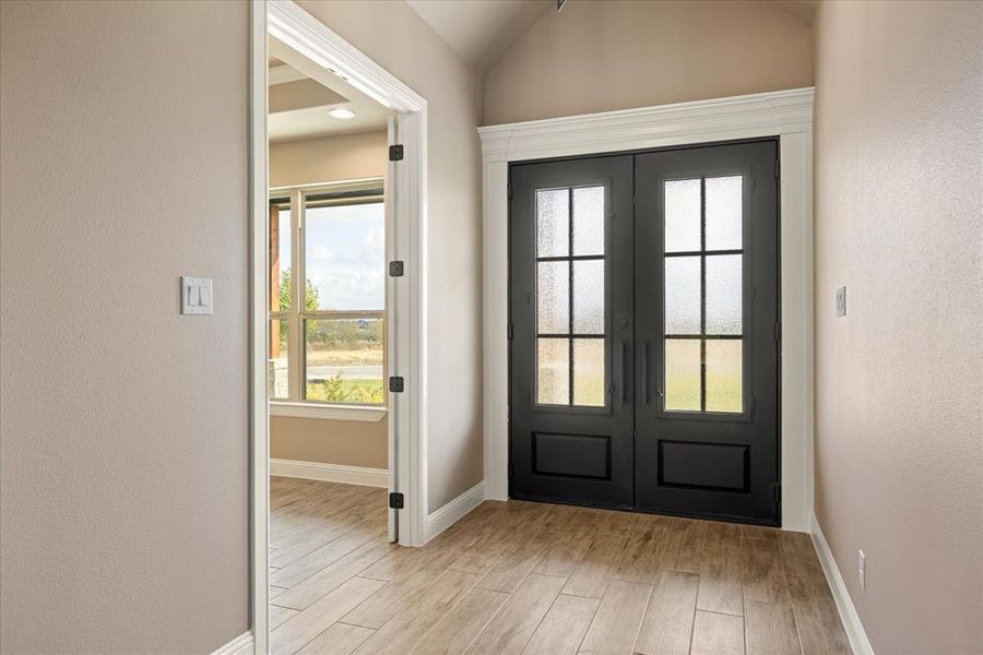 Doorway to outside with light hardwood / wood-style flooring, french doors, and vaulted ceiling