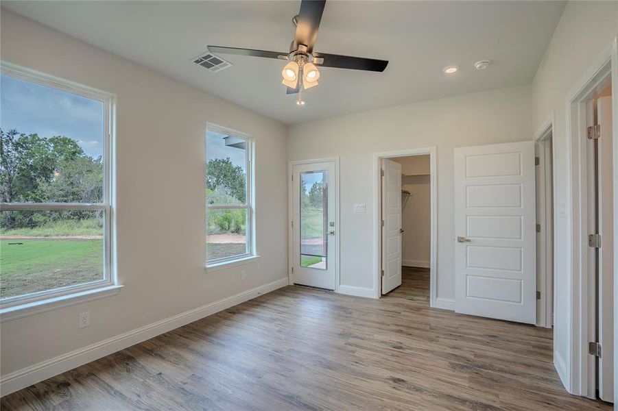 Unfurnished bedroom with access to exterior, ceiling fan, hardwood / wood-style floors, and a spacious closet