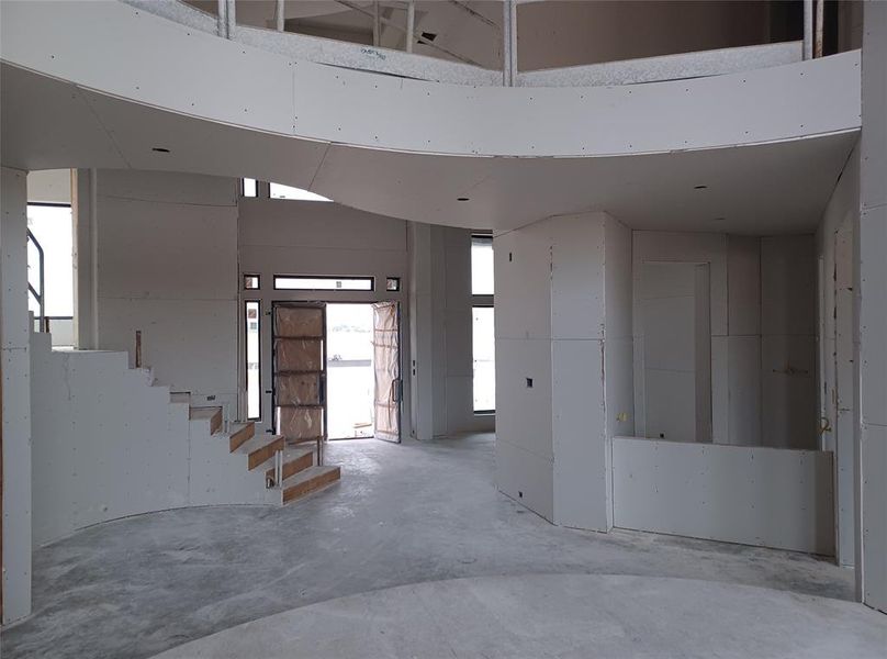 View from elevated 2-story living room towards the front of the home with grandiose foyer with winding staircase and butler's pantry off of formal dining room kitchen.