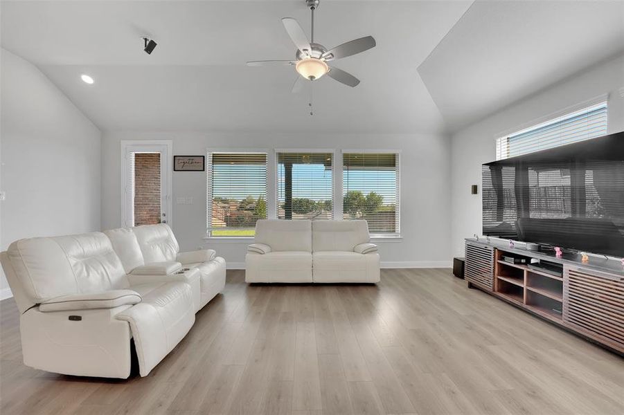 Living room featuring ceiling fan, lofted ceiling, and light hardwood / wood-style flooring