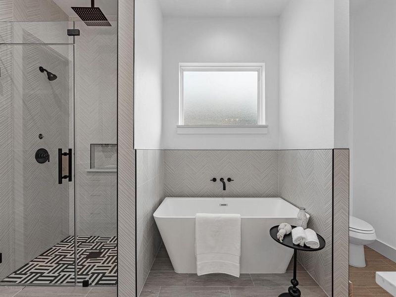 The primary bathroom showcases floor-to-ceiling tile in the stand-up shower, complemented by two shower heads. The soaking tub is elegantly designed with perfect natural lighting.
