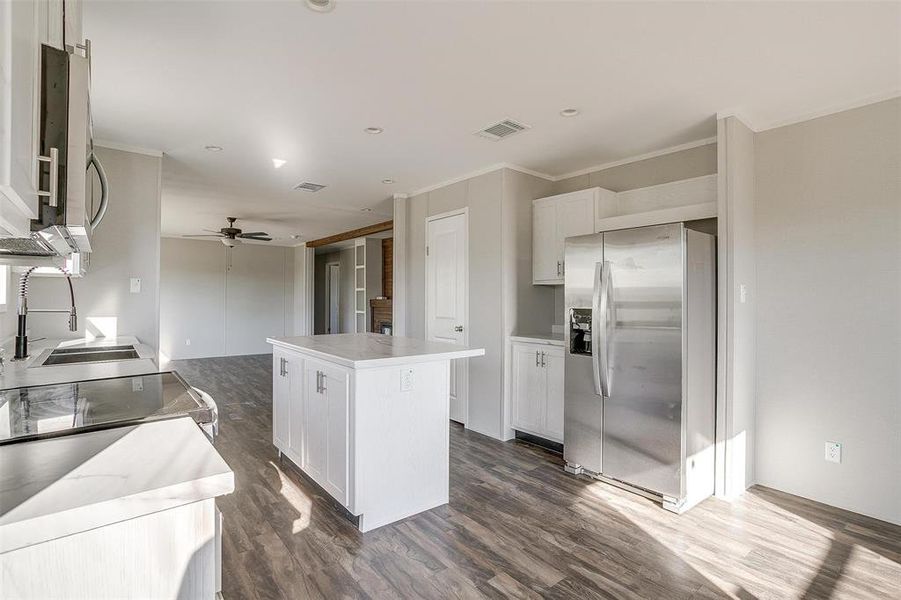 Kitchen with dark hardwood / wood-style floors, a center island, stainless steel appliances, white cabinetry, and ceiling fan