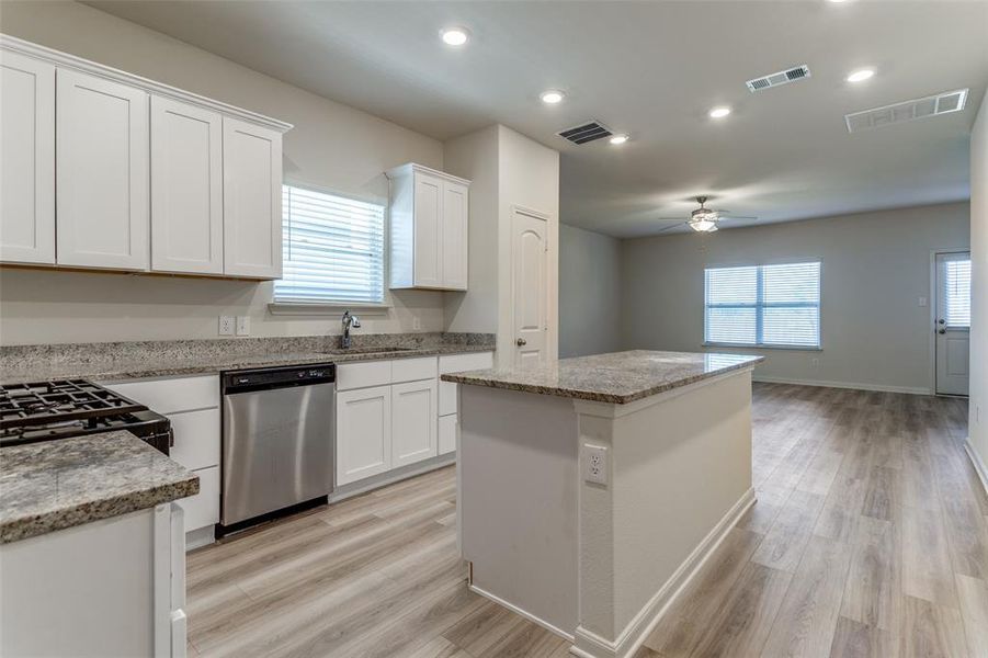 Kitchen featuring stainless steel dishwasher, ceiling fan, light hardwood / wood-style flooring, and a kitchen island