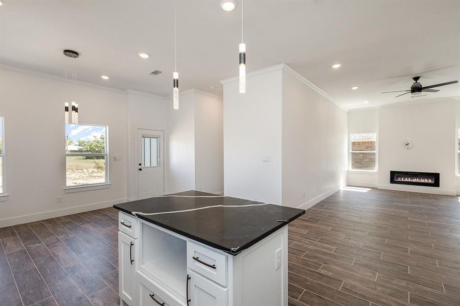 Kitchen with dark wood-type flooring, white cabinets, a kitchen island, ceiling fan, and decorative light fixtures