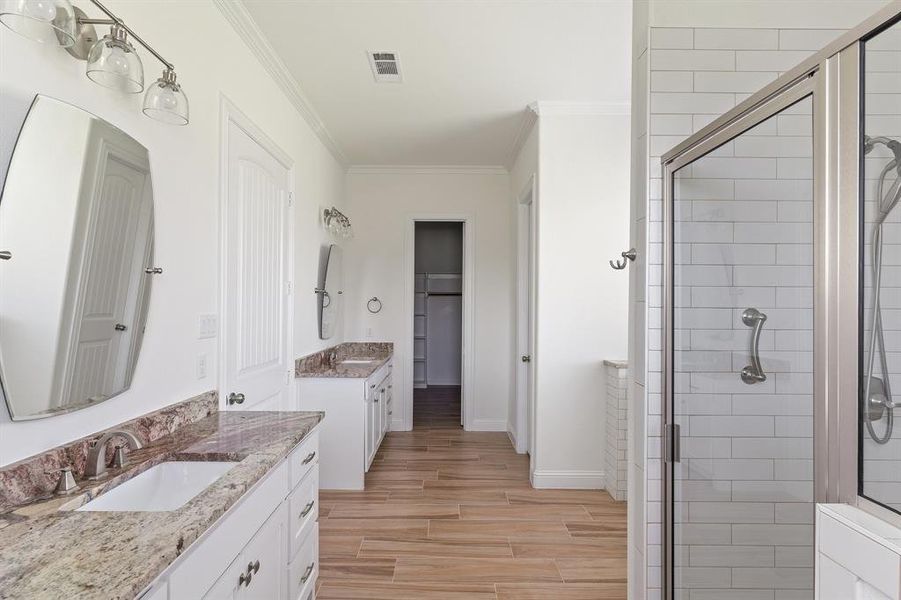 Bathroom with a shower with door, crown molding, double vanity, and hardwood / wood-style floors