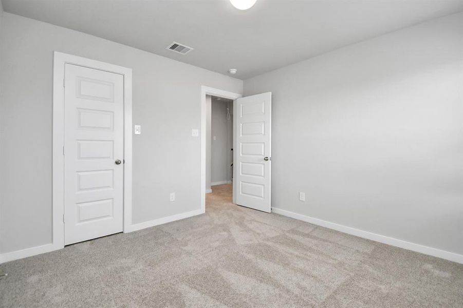 Secondary bedroom features plush carpeting, large windows that let in plenty of natural light, bright paint, and spacious closets. Sample photo of completed home with similar floor plan. Actual colors and selections may vary.