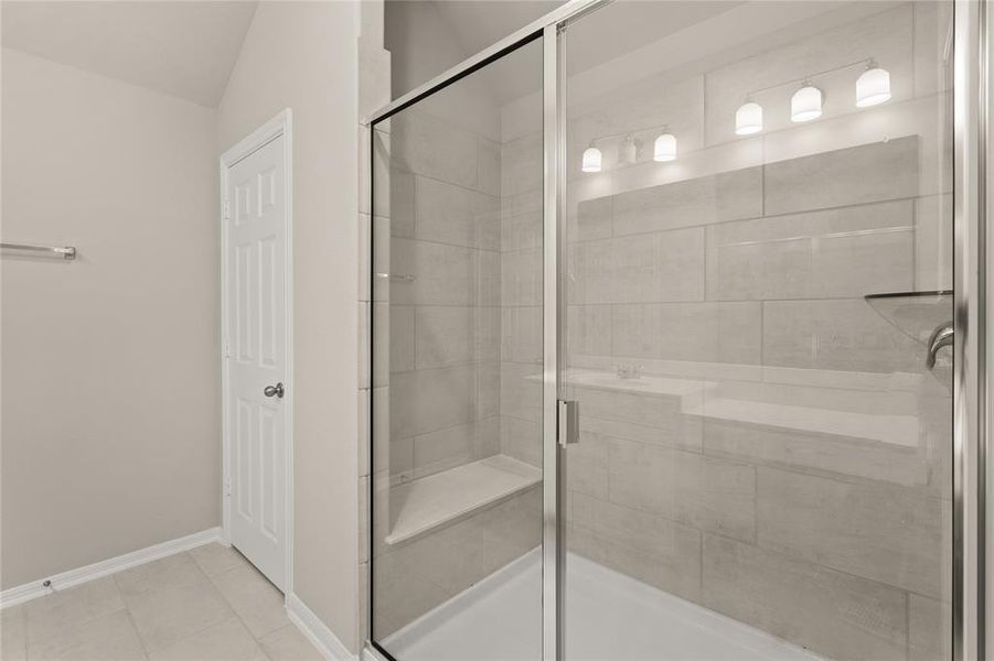 This additional view of your primary bathroom features tile flooring, fresh paint, and a large walk-in shower.