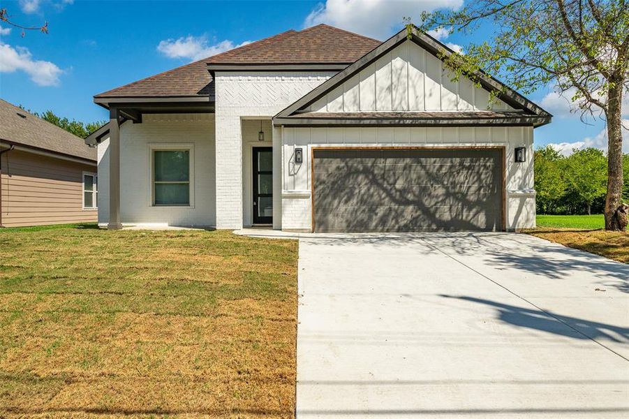 View of front of home featuring a front lawn and a garage