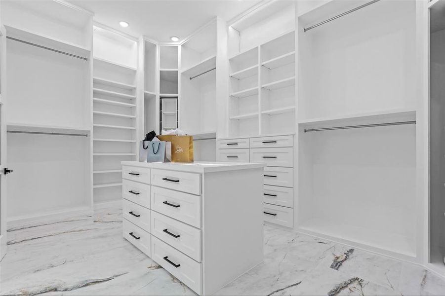 Primary closet with lit jewelry display cabinet, under cabinet lighting, and rotating corner display cabinetry