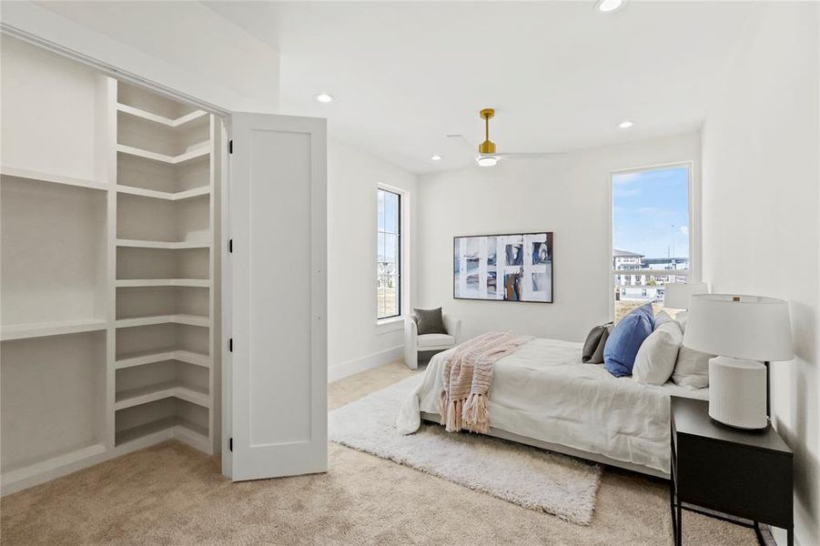 Carpeted bedroom featuring ceiling fan and multiple windows