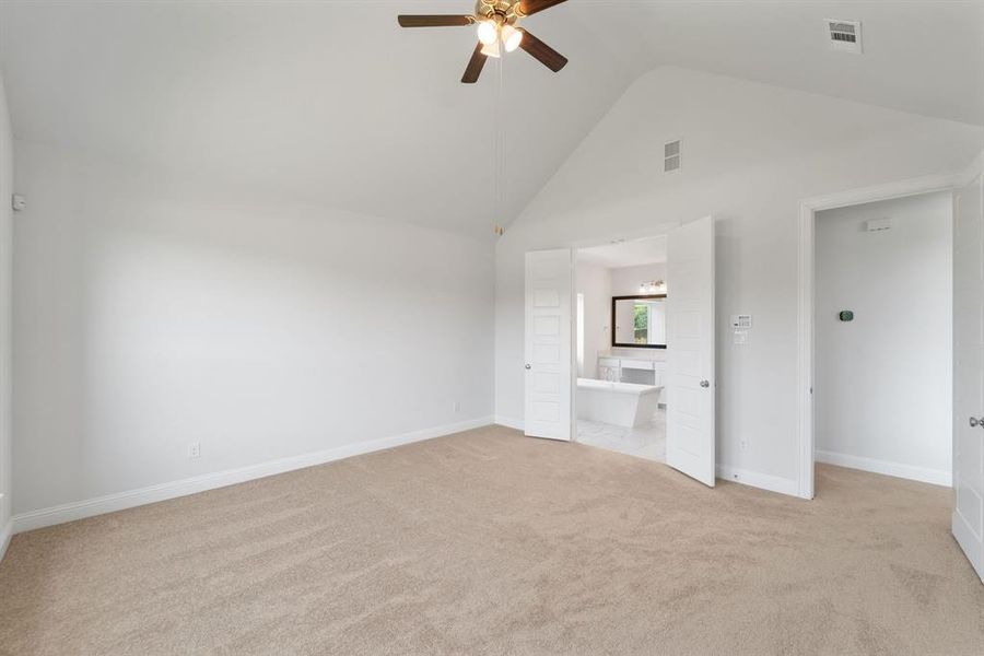Unfurnished living room featuring light carpet, high vaulted ceiling, and ceiling fan