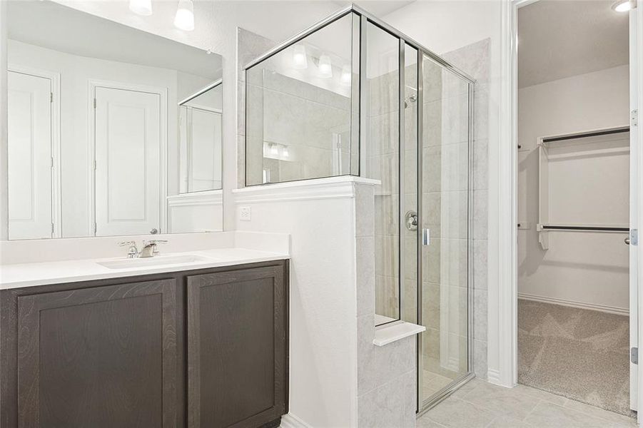 Bathroom featuring a shower with shower door, large vanity, and tile floors