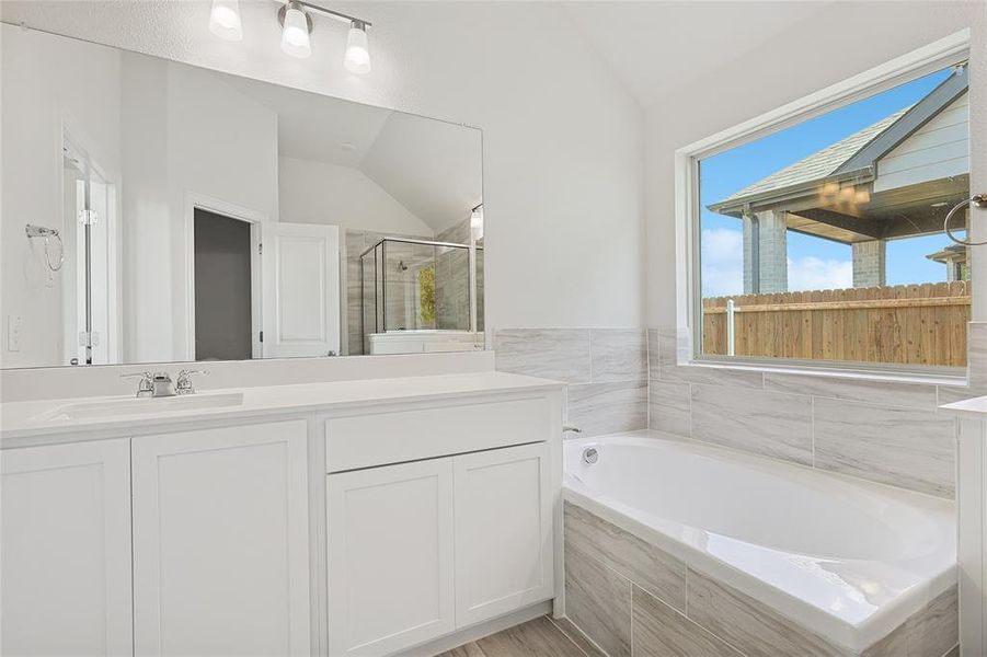 Bathroom with vanity, vaulted ceiling, and plus walk in shower