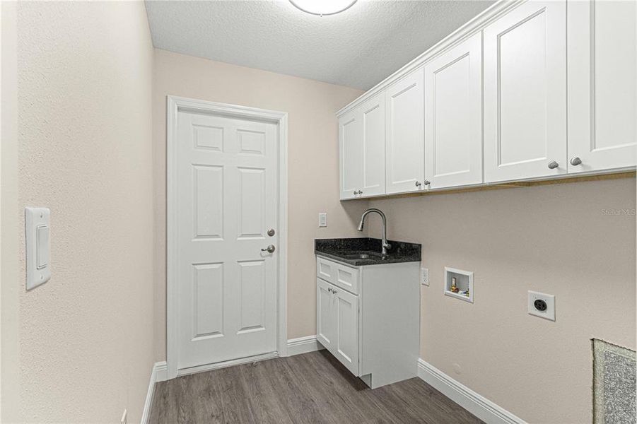 Laundry room with granite countertop sink and plenty of cabinets for storage