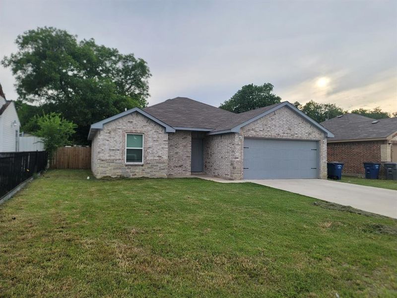 Ranch-style house featuring a garage and a yard