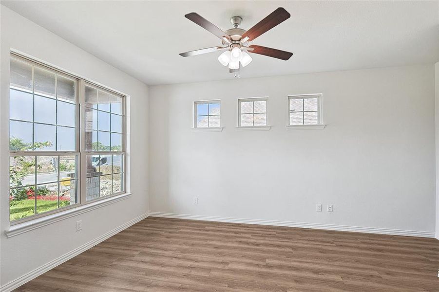 Empty room with a wealth of natural light, hardwood / wood-style flooring, and ceiling fan