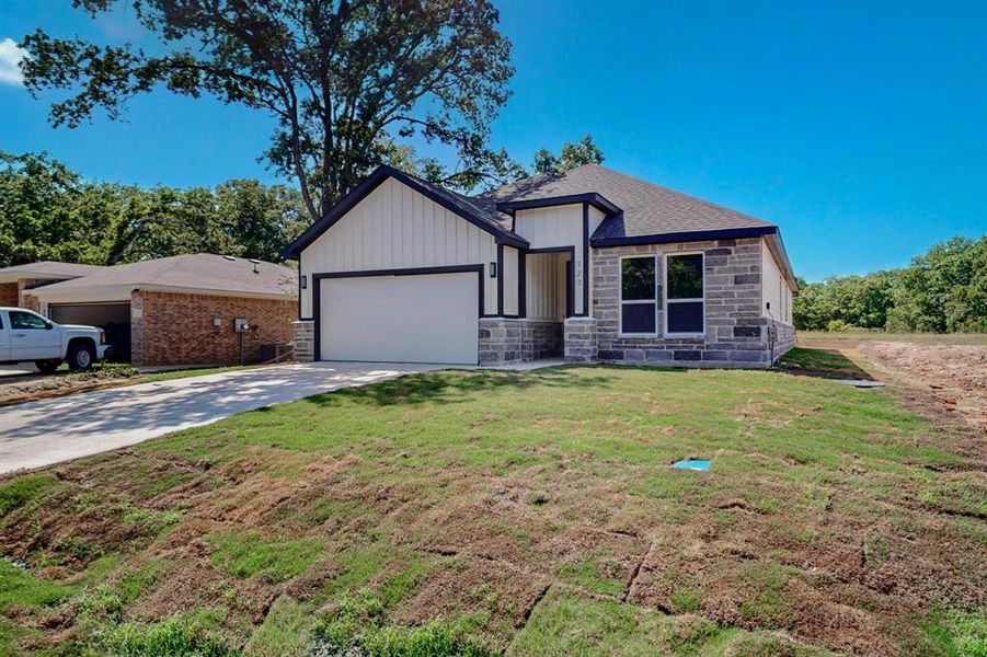 View of front of property featuring a garage and a front lawn