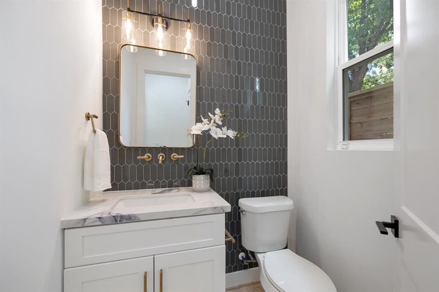 The first floor powder room boasts ceiling height backsplash, designer sconces and beautiful countertops.