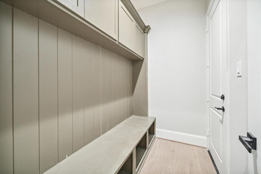 This is a modern, minimalist mudroom with built-in storage and a bench, featuring clean lines and neutral tones. Ideal for organizing outerwear and shoes.