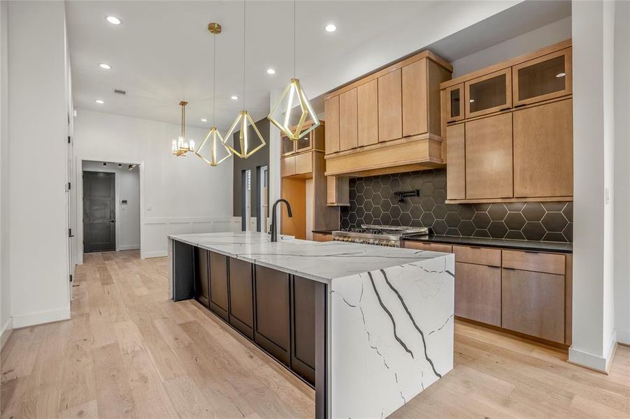 Custom-designed vent hood, classic backsplash, and all custom cabinets adorn this timeless gourmet kitchen with modern hardware and functionality.