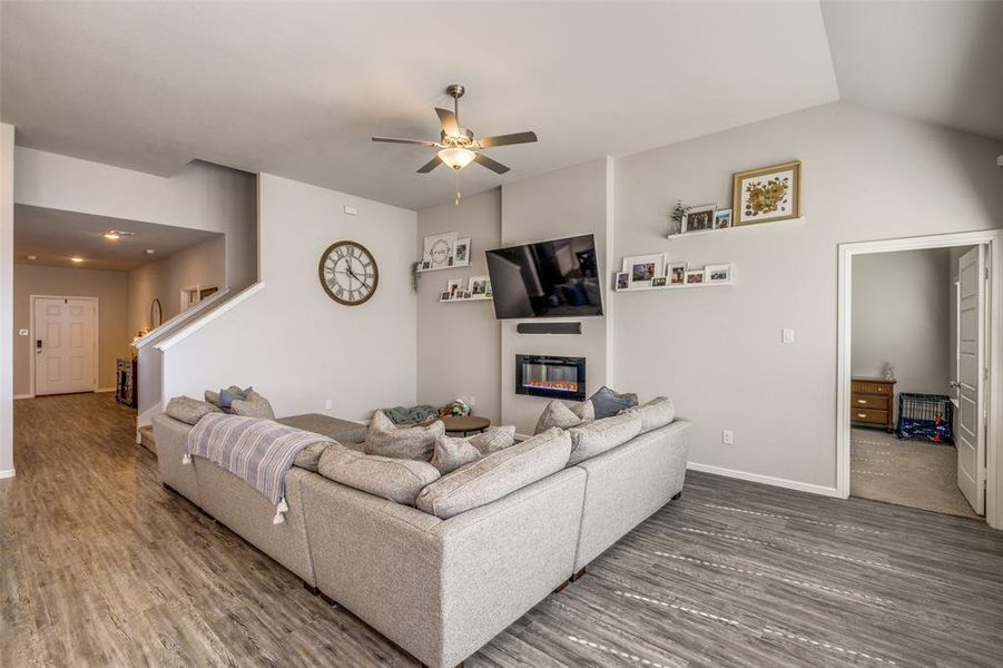 Living room featuring 11' sloped ceiling, ceiling fan, and LVP wood-style floors