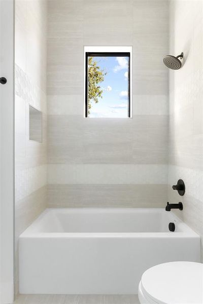 Bathroom with tiled shower / bath and toilet