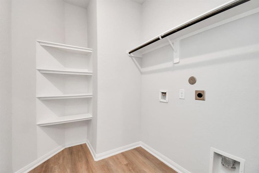 A spacious utility room with ample shelving for organization. It features connections for both gas and electric dryers, making it versatile and functional for all laundry needs.