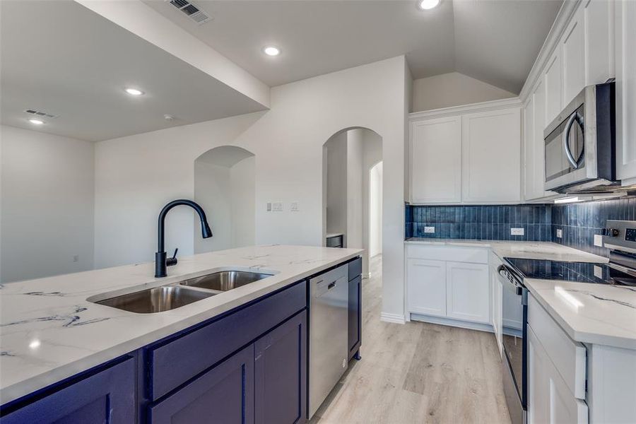 Kitchen featuring white cabinets, stainless steel appliances, light hardwood / wood-style floors, and sink