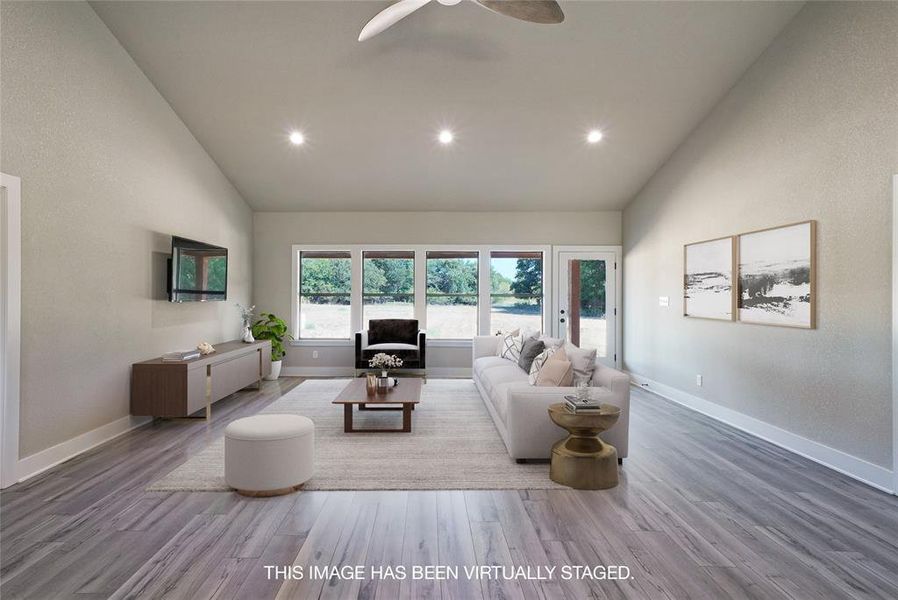 Living room with ceiling fan, high vaulted ceiling, and hardwood / wood-style flooring