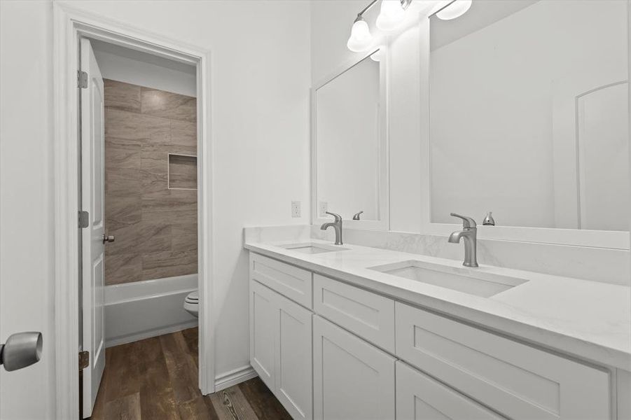 Full bathroom with vanity, toilet, hardwood / wood-style flooring, and tiled shower / bath combo