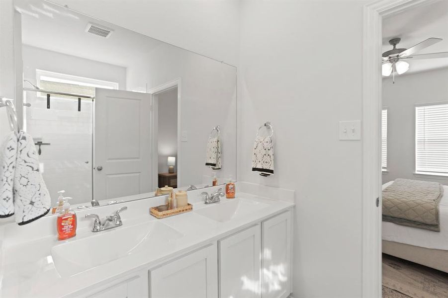 Experience the luxury of the master suite's spacious en-suite bathroom, featuring dual vanities and a sleek, walk-in shower adorned with classic white subway tiles.