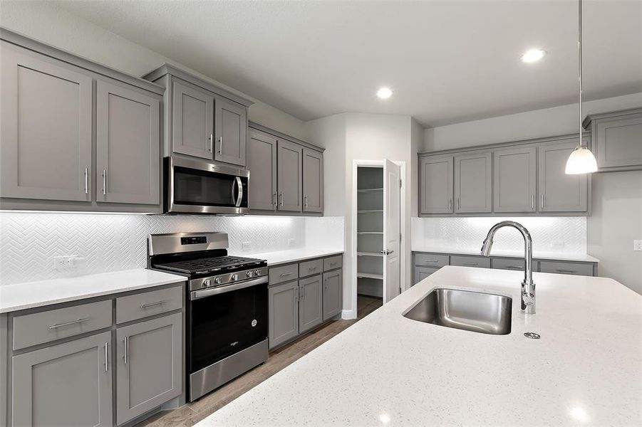 Kitchen featuring stainless steel appliances, sink, gray cabinets, and hanging light fixtures