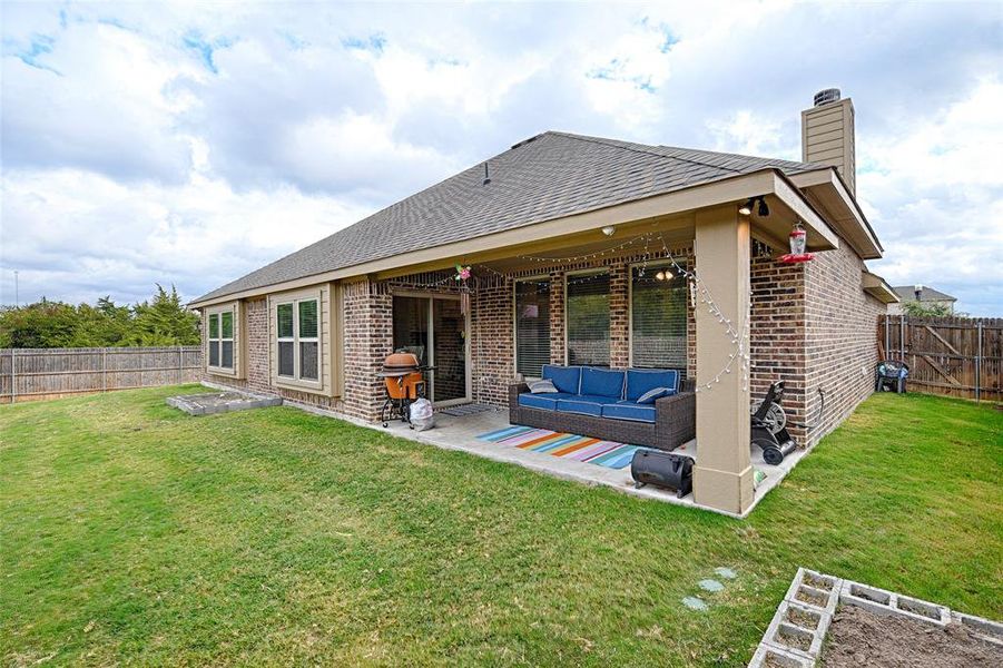 Back of property featuring a patio, an outdoor living space, and a lawn