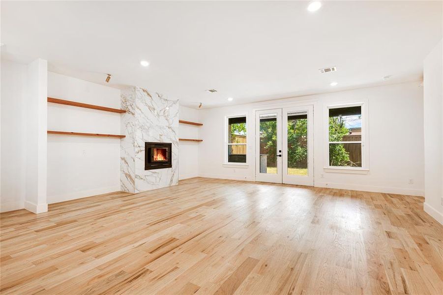 Unfurnished living room featuring light hardwood / wood-style floors, french doors, and a premium fireplace