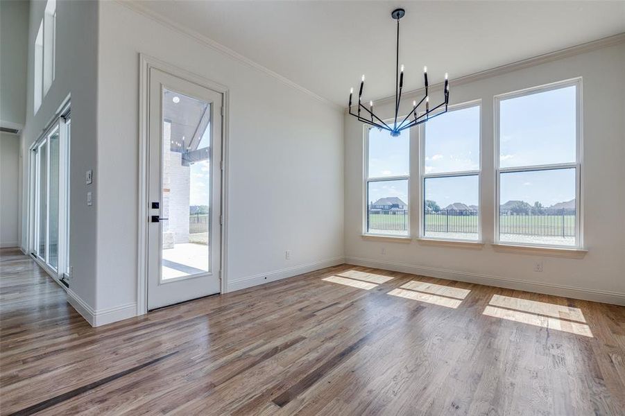 Unfurnished dining area featuring an inviting chandelier, light hardwood / wood-style flooring, ornamental molding, and a wealth of natural light