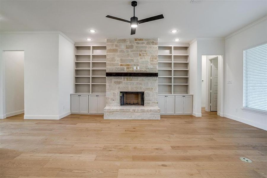 Unfurnished living room with built in shelves, a fireplace, ceiling fan, and plenty of natural light