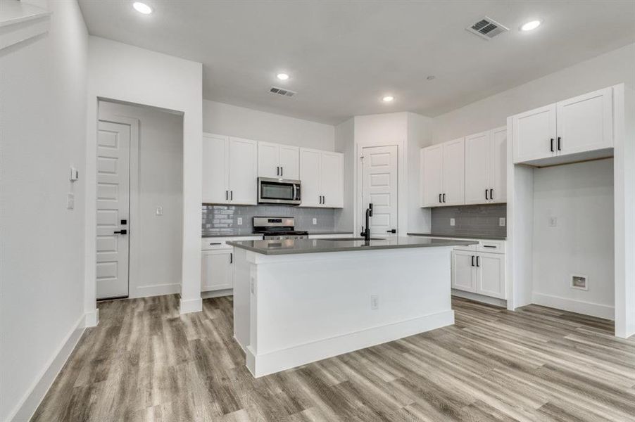 Kitchen featuring white cabinets, a kitchen island with sink, and stainless steel appliances