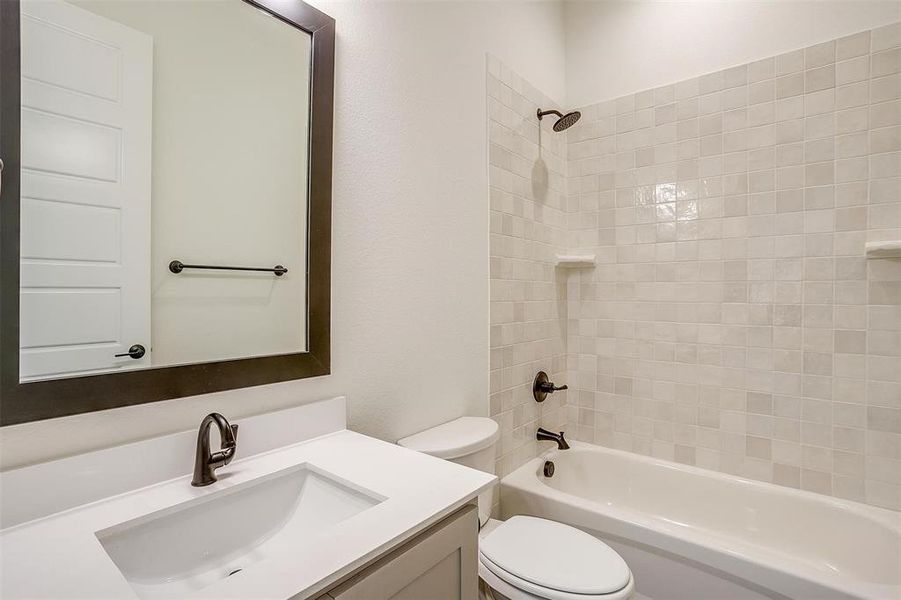 Full bathroom featuring vanity, tiled shower / bath combo, and toilet