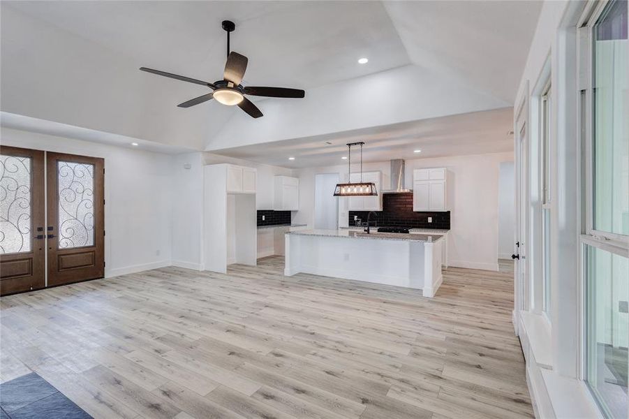 Kitchen with an island with sink, white cabinetry, french doors, and light hardwood / wood-style flooring