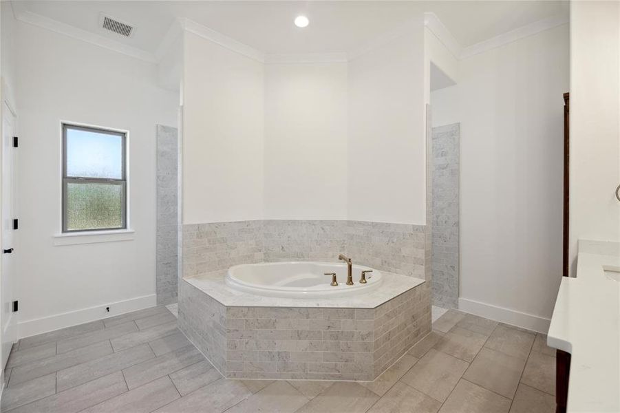 Bathroom featuring a relaxing tiled tub, vanity, crown molding, and tile patterned floors