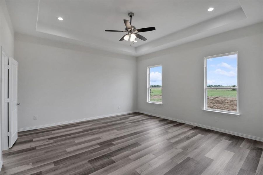 Unfurnished room with hardwood / wood-style floors, ceiling fan, and a tray ceiling