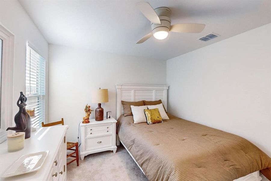 Bedroom with ceiling fan and light colored carpet