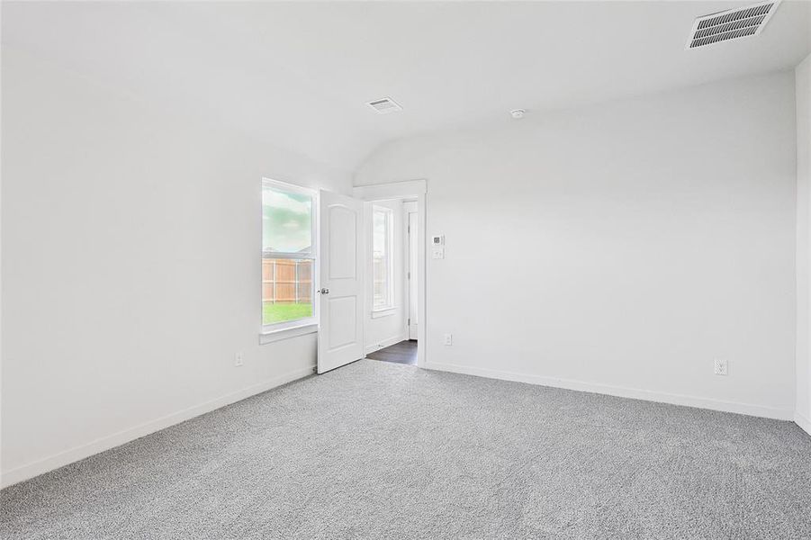 Carpeted spare room featuring lofted ceiling